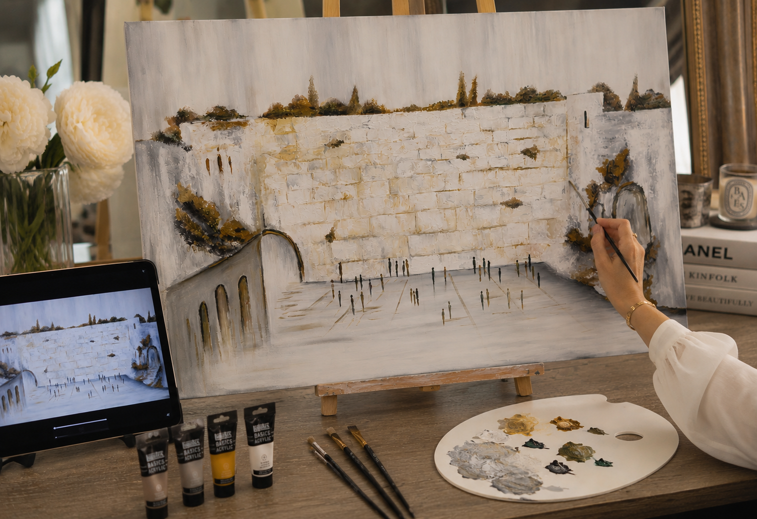 Woman painting a textured Kosel canvas alongside the tutorial video, paints and brushes at hand